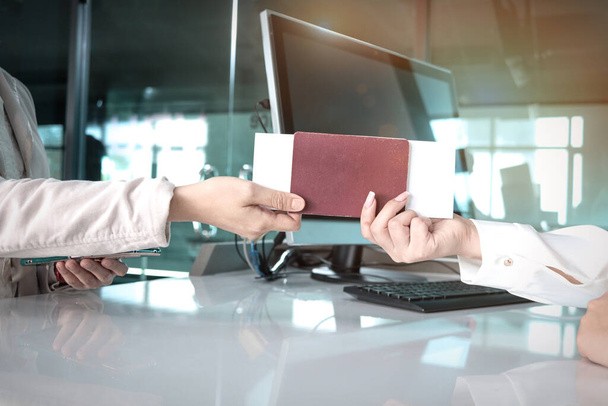 Hand einer Reisenden, die Reisepass und Bordkarte an das Personal des Passagier-Service-Agenten weitergibt, um Informationen am Check-in-Bereich des Flughafenterminals, auf Reisen im Urlaub oder auf Geschäftsreisen zu überprüfen - Foto, Bild
