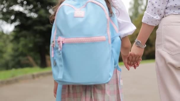 学校に通う途中で母親と一緒にいる小さな女の子. 思いやりのある母親は,彼女が学校に歩いているときに娘の手を優しく握ります. - 映像、動画