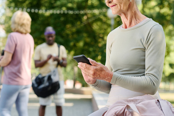 Close-up of senior woman using smartphone after sport training outdoors - Photo, Image