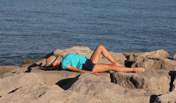 молодая девушка-модель на скале у моря летом - Фото, изображение