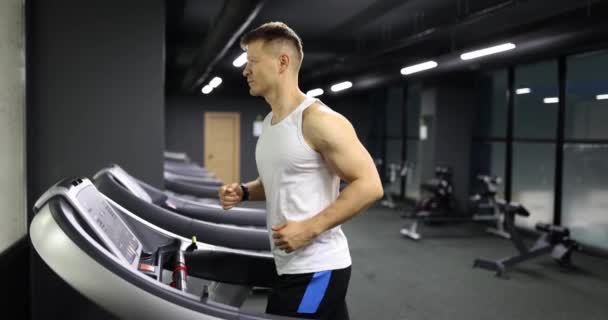 Atletický muž běhá na běžeckém pásu a cvičí na kardiologii v tělocvičně. Fitness muž dělá kardio školení ve sportovním klubu - Záběry, video