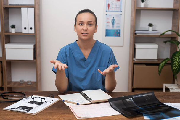 Telehealth Professional: U svého stolu, žena lékař mluvit s kamerou s pacientem on-line, symbolizující telemedicína revoluce.  - Fotografie, Obrázek