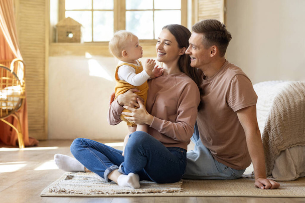 Πορτρέτο των χαρούμενων νέων γονέων που διασκεδάζουν με το βρέφος γιο τους στο σπίτι, αγάπη Καυκάσια οικογένεια των τριών με αξιολάτρευτο μωρό Αγκαλιάζοντας και χαμογελώντας, απολαμβάνοντας το χρόνο μαζί, αντιγραφή χώρο - Φωτογραφία, εικόνα