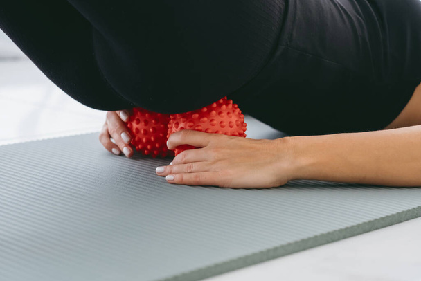 女性は,腰の痛みを和らげるために2つの小さなボールを入れ,筋肉と痛みをマッサージし,サクラムと脊椎の痛みを和らげるための演習を行います. 筋肉のリラックスとストレッチ - 写真・画像
