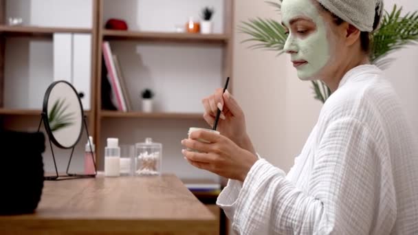 Maîtrise des soins : Après le bain, enveloppée dans une serviette, elle applique habilement un masque facial pour une peau anti-âge, hydratante et impeccable.  - Séquence, vidéo
