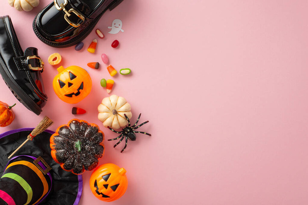 Dive into Halloween fun with this delightful costume ensemble for girls. Top view of petite leather loafers, enchanting hat, candy corn and decor on pastel pink setting. Advertise effectively here - Photo, Image