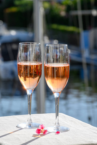 Letnia impreza, picie francuskiego brut rose szampana wina musującego w szklankach w porcie jachtowym Port Grimaud niedaleko Saint-Tropez, wakacje na Riwierze Francuskiej, Var, Francja - Zdjęcie, obraz