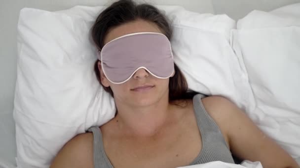 Uykuya dalmak için maskeli sakin kadın, yastığının üzerinde, sağlıklı uyku düzeninin bir sembolü olan rahat bir battaniyenin altında huzur içinde yatıyor..  - Video, Çekim