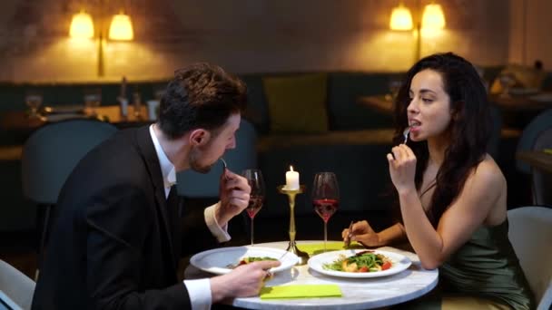 Romantikus pár salátát eszik és vörösbort isznak, miközben az étteremben randiznak. Életstílus, szerelem, kapcsolati koncepció. Lassú mozgás. - Felvétel, videó