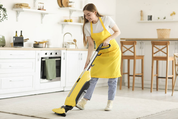 Jeune femme aspirant tapis dans la cuisine - Photo, image