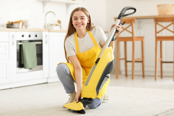 Young woman with vacuum cleaner in kitchen - Photo, Image