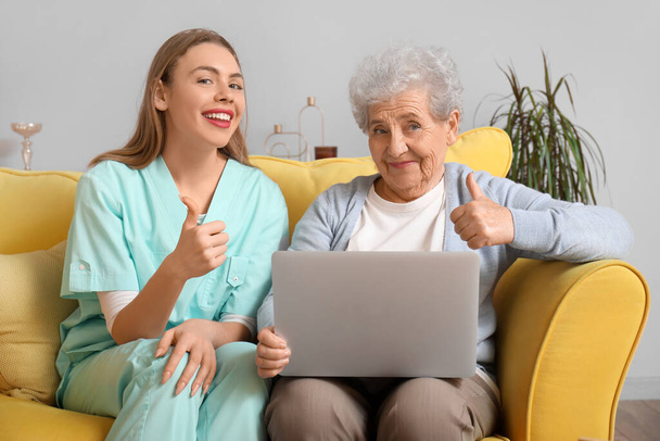 Pflegerin zeigt Seniorin zu Hause Daumen nach oben - Foto, Bild