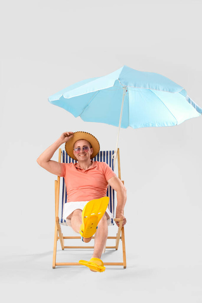 Mature man relaxing in deck chair on light background - Photo, Image