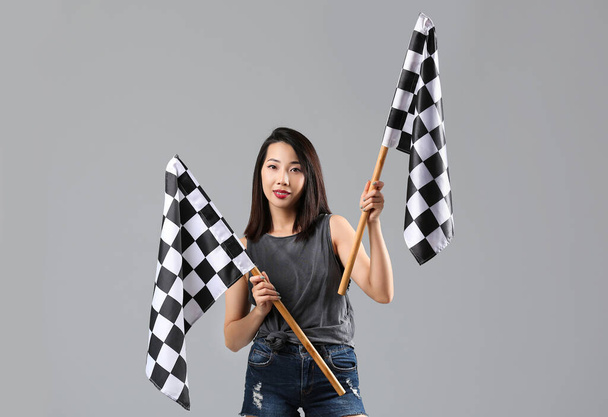 Beautiful Asian woman with racing flags on grey background - Photo, Image