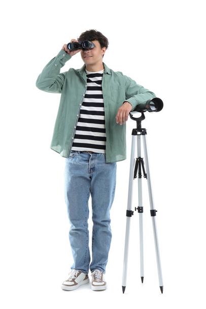 Young man with telescope and binoculars on white background - Photo, Image