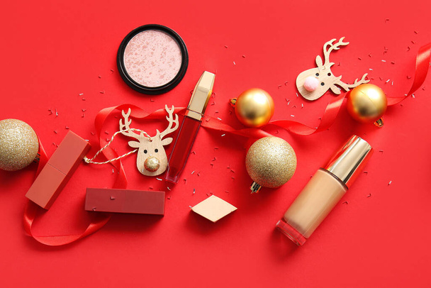 Σύνθεση με διακοσμητικά καλλυντικά και χριστουγεννιάτικη διακόσμηση σε κόκκινο φόντο - Φωτογραφία, εικόνα