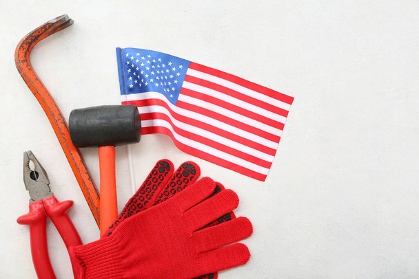Handschuhe, verschiedene Werkzeuge und USA-Flagge auf weißem Hintergrund. Feierlichkeiten zum Tag der Arbeit - Foto, Bild