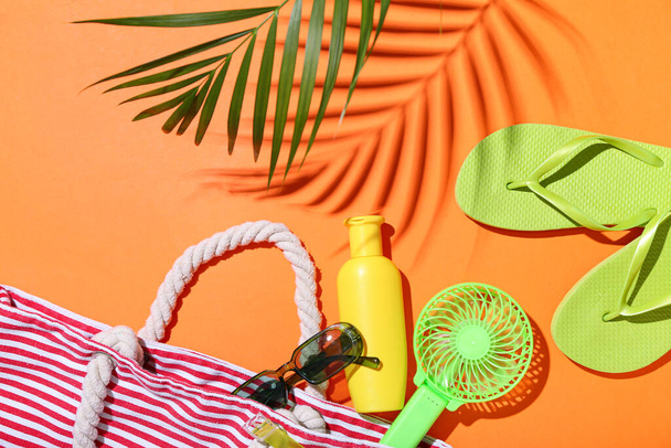 オレンジ色の背景に緑のポータブル電気ファンとビーチアクセサリーと組み合わせる - 写真・画像
