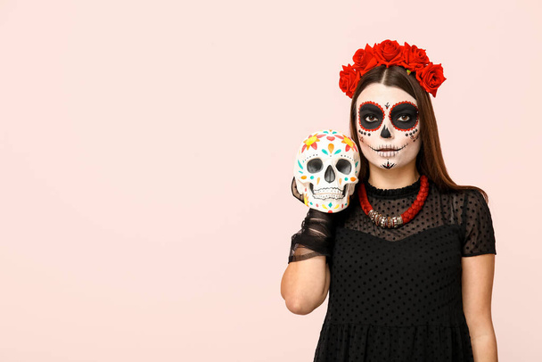 Young woman dressed for Halloween with painted skull on light background - Photo, Image