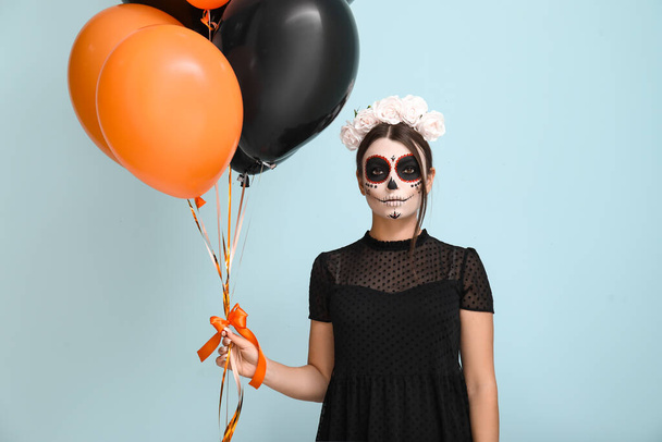 Young woman dressed for Halloween with balloons on blue background - Photo, Image