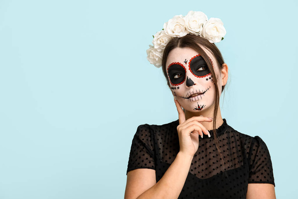 Nachdenkliche junge Frau zu Halloween auf blauem Hintergrund - Foto, Bild