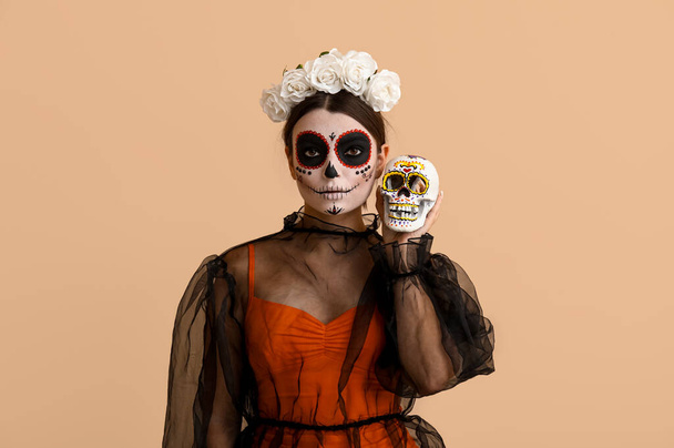 Fiatal nő öltözött Halloween festett koponya bézs háttér - Fotó, kép