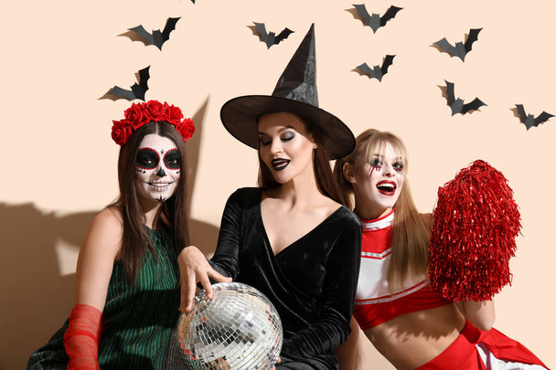 Γυναίκες φίλες ντυμένες για το Halloween με ντίσκο μπάλα κοντά σε μπεζ τοίχο - Φωτογραφία, εικόνα