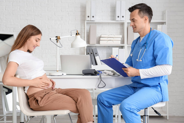 Νεαρή έγκυος γυναίκα επισκέπτεται γιατρό στην κλινική - Φωτογραφία, εικόνα