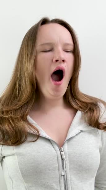 väsynyt haukottelu kehyksessä teini tyttö väsynyt opiskelemaan töihin puhuminen haukottelu suu auki peittää kasvonsa kädellään kauniit hiukset hyvin hoidettu. tylsää elämää studiossa - Materiaali, video