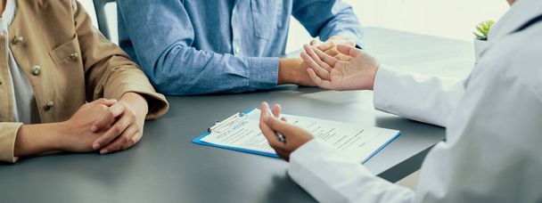 Doctor show medical diagnosis report and providing compassionate healthcare consultation to young couple patient in doctor clinic office. Doctor appointment and medical consult concept. Neoteric - Photo, Image
