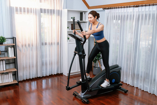 自宅で楕円形ランニングマシンで走っているエネルギーと強い運動アジアの女性. 家庭でのトレーニングとトレーニングで健康的なライフスタイルへのフィット感とコミットメントを追求します. ヴィゴーラス - 写真・画像