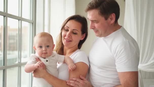 Happy family at home. Mother father holding little toddler child. Mom dad baby girl relax playing having fun together. Woman man hugging embracing baby with love care. Parent of breast feeding baby - Footage, Video