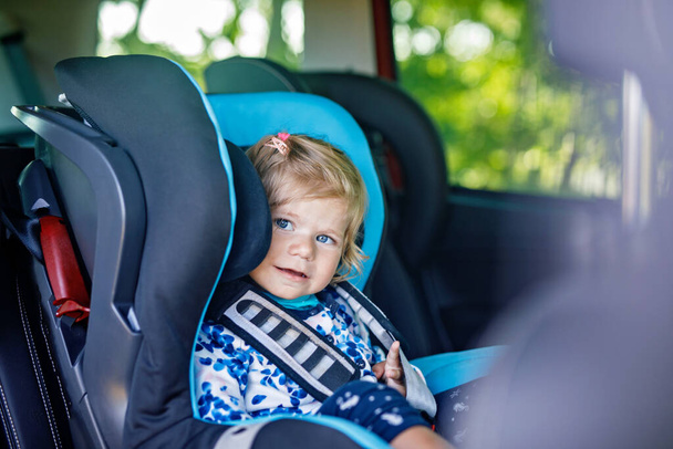 Adorabile bambina con gli occhi azzurri seduta sul sedile di sicurezza dell'auto. Bambino bambino in vacanza in famiglia e Jorney. Sorridente bambino felice durante l'ingorgo stradale
 - Foto, immagini