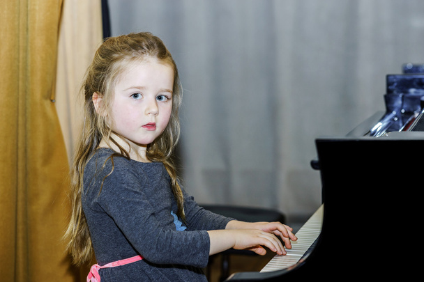 Cute little girl playing grand piano - 写真・画像