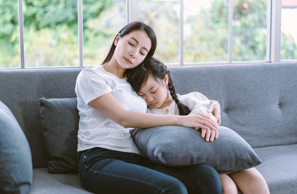 Asyalı anne, evdeki oturma odasında kanepede otururken uyuyan tatlı kızına sarılıyor. Sağlık sigortası tıbbi aşkı Asyalı kadın yaşam tarzı fotokopi alanı ile anneler günü. - Fotoğraf, Görsel