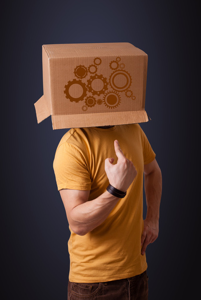 Young man gesturing with a cardboard box on his head with spur w - 写真・画像