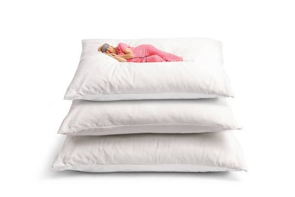 Woman in pajamas sleeping on a pile of three big pillows isolated on white background - Φωτογραφία, εικόνα