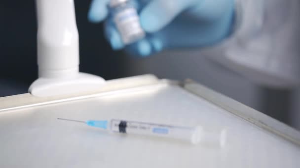 Coltivazione infermiera irriconoscibile in guanti di lattice che dimostra il flaconcino di vaccino Covid 19 posto sul carrello medico vicino alla siringa - Filmati, video