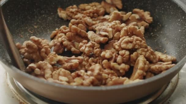 Ylhäältä tunnistamaton kokki paistamiseen saksanpähkinät pannulla liedellä lounaan aikana valmistelu keittiössä päivänvalossa - Materiaali, video
