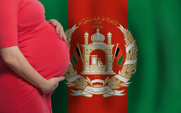 Афганський живіт вагітної жінки на фоні прапора Афганістану - Фото, зображення