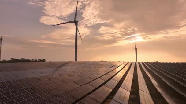 vista aérea do pôr do sol de painéis de energia solar e turbinas eólicas no campo, fonte de energia renovável - Filmagem, Vídeo