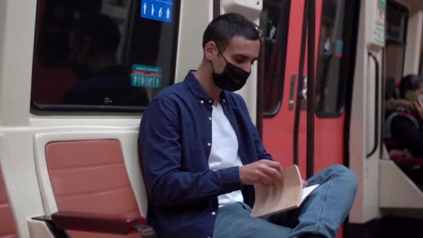 Anonymní mladý muž student v příležitostné oblečení otevírací sešit při přípravě na zkoušku ve veřejné dopravě - Záběry, video