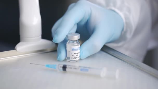 Enfermera no reconocible en guantes de látex que demuestra el vial de vacuna de Covid 19 colocado en el carro médico cerca de la jeringa - Metraje, vídeo