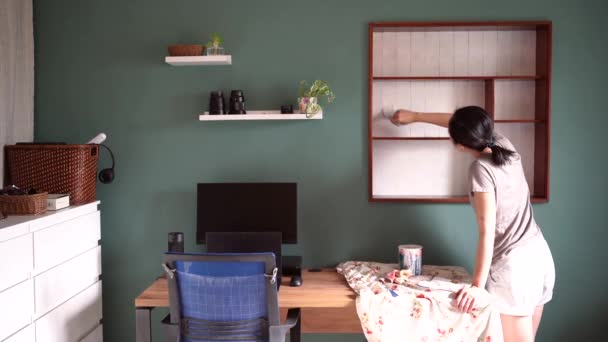 Vista posterior de la mujer étnica con pintura al pincel estantes de madera en color blanco al renovar muebles - Metraje, vídeo