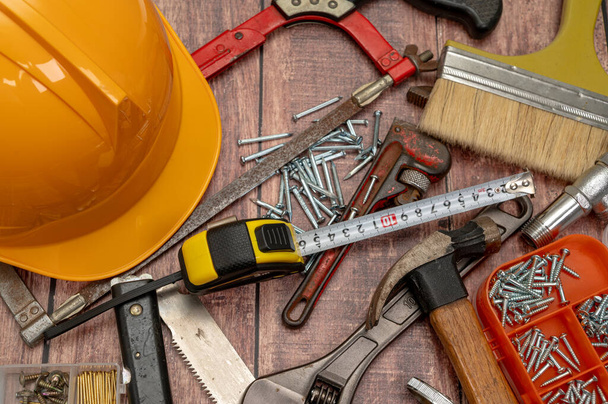 Em uma placa de madeira, uma variedade de ferramentas necessárias para o reparo doméstico são colocadas irregularmente. - Foto, Imagem