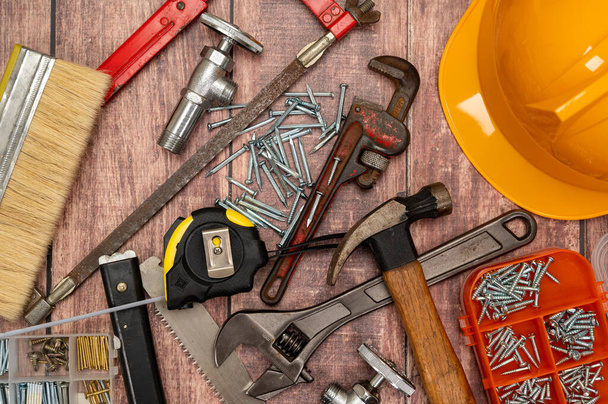 Puulevyllä on epäsäännöllisesti sijoitettu erilaisia kodin korjaamiseen tarvittavia työkaluja.. - Valokuva, kuva