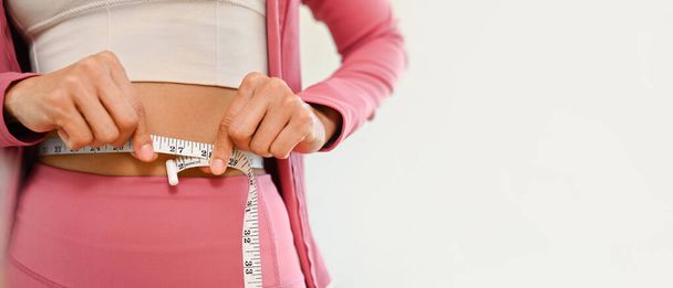 Giovane donna magra irriconoscibile che misura la vita con nastro adesivo. Dieta, perdita di peso e stile di vita sano concetto. - Foto, immagini