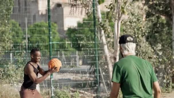 Νεαρός Αφροαμερικανός σε αναπηρική καρέκλα διασκεδάζει παίζοντας μπάσκετ με φίλους  - Πλάνα, βίντεο