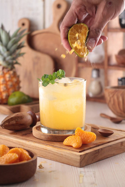 bicchiere di succo d'ananas fresco con cubetti di ghiaccio e menta sul tavolo - Foto, immagini