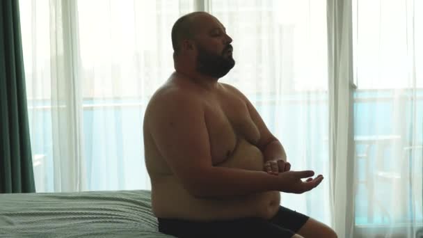 Overweight man measures pulse on hand, doing breathing exercises during seizure sitting in bed. Breath difficulties, asthma, postcovid complications. Health problems of excess weight people concept. - Footage, Video